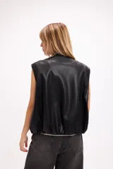 Chaleco de cuero sintético negro, con cierre frontal de botones a presión, bolsillos laterales y ruedo regulable con cordón elástico.