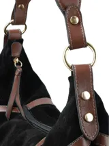 Cartera tipo bolsón de gamuza negra con detalles en cuero liso marrón y flecos largos en todo el borde inferior. Cuenta con una correa de hombro integrada y cierre central.