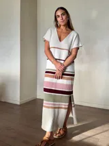 Vestido largo de tejido de punto de algodón, con diseño rayado en tonos marrón, celeste, blanco y rojo. Presenta escote en V con detalle de costura en contraste, mangas cortas, silueta holgada y aberturas laterales en el dobladillo.