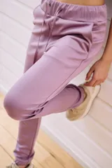 Pantalón babucha deportivo color lila, con elástico en la cintura y puños, cordones regulables y dos bolsillos laterales.