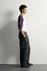 Pantalón cargo de corte relaxed fit, color negro con efecto lavado y estampado de salpicaduras blancas. Cuenta con bolsillos laterales con solapa en las perneras, pinzas en las rodillas y cierre frontal con botón y cremallera.