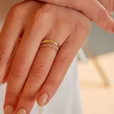 Anillo doble de oro amarillo 18k, compuesto por una banda fina con engaste de pequeños brillantes y otra banda lisa con un brillante central solitario.