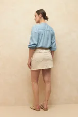 Minifalda de jean color beige claro, con corte en A y bolsillos delanteros curvos.