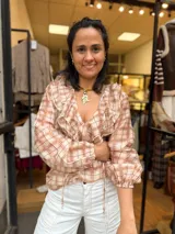 Blusa a cuadros con escote en V y volados que lo bordean, de mangas largas abullonadas con puños elásticos y lazos colgantes en el dobladillo.