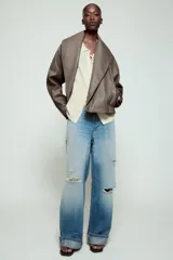 Cazadora Zara Woman Collection de efecto piel con cuello solapa ancho, manga larga, bolsillos delanteros y bajo elástico. Presenta un cierre frontal cruzado con botón a presión.