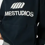 Hoodie oversize color negro de algodón, con capucha, bolsillo frontal tipo canguro y estampado frontal con el texto y logotipo de EM ESTUDIOS.