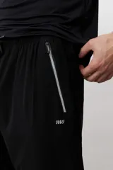 Pantalón deportivo de corte recto y ajuste holgado, color negro, con cintura elástica con cordón ajustable, bolsillos laterales con cierre y detalle de logo pequeño en el muslo.