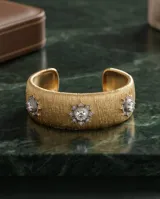 Brazalete ancho de bronce con acabado texturizado dorado, adornado con tres apliques en forma de estrella con circonias incrustadas.