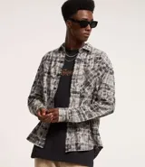 Camisa masculina de franela con estampa de cuadros en tonos grises y blancos, cuello inglés, abotonada, manga larga, modelo comfort con bolsillo en el pecho.