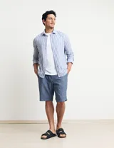 Camisa de lino a rayas verticales color beige y blanco, de corte clásico, con cuello abotonado y mangas largas.