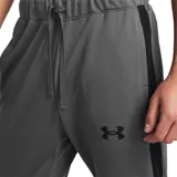 Conjunto deportivo Under Armour para hombre, compuesto por una campera con cierre frontal y cuello alto, y un pantalón de corte ajustado. Ambas piezas presentan el logo de la marca en color negro y franjas laterales oscuras.