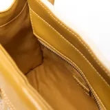 Cartera tipo tote de material textil color beige con detalles y asas en cuero sintético color mostaza. Cuenta con un bolsillo externo frontal con cierre y el logo de la marca impreso, doble asa de mano y correa de hombro ajustable y desmontable.