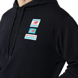 Canguro con capucha New Balance, color negro, con bolsillo frontal tipo canguro y cordones ajustables. Presenta un diseño gráfico con parches superpuestos en el pecho con el logo de la marca.