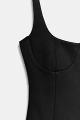 Vestido corto de tejido de punto elástico, con escote redondo, tirantes anchos y costuras marcadas que definen el busto. Presenta un diseño ajustado con cierre lateral oculto.