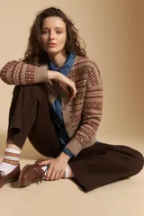 Cardigan corto de tejido jacquard con diseño geométrico en tonos beige y crema, con cierre frontal de botones y cuello redondo.