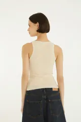 Musculosa negra con escote redondo ribeteado en encaje, detalle de botones frontales y diseño ajustado.