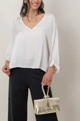 Blusa italiana de viscosa color beige, de calce holgado, con escote en V y detalle de lurex. Presenta mangas tres cuartos y diseño fluido.
