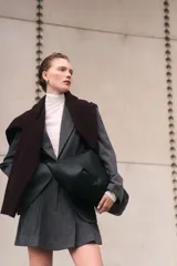 Blazer de mujer gris oscuro con estampado Príncipe de Gales (a cuadros). Presenta solapas de muesca, cierre frontal de dos botones, hombreras y bolsillos delanteros con solapa.