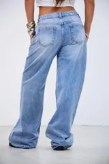 Pantalón de denim tiro bajo, color gris lavado, de corte recto y holgado. Presenta una línea de tachas metálicas pequeñas a lo largo de la costura lateral externa.