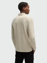 Remera polo de piqué de algodón color beige, de manga larga y corte entallado.