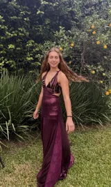 Vestido largo bordó con escote en V, cut-outs laterales bajo el busto, breteles finos cruzados en la espalda y falda larga combinada con paneles godet en el ruedo.