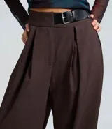 Pantalón sastre de corte barrel, color gris oscuro, con cintura alta, pinzas delanteras y diseño de pierna ancha.