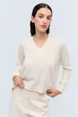 Sweater de punto color crema, con escote en V y calce holgado.