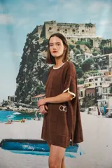 Vestido corto de tejido calado color marrón, con patrón cuadrado y logo bordado a mano en el frente. Presenta terminaciones a contratono en escote redondo y mangas cortas.