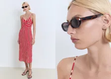 Vestido midi de tirantes finos ajustables, con escote en pico y detalle fruncido en la parte frontal. Presenta un diseño recto con estampado de rayas verticales en tonos rojo y blanco.