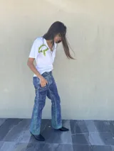 Pantalon de tiro medio y corte recto, confeccionado en tela con textura marcada y acabado rustico. Presenta un estampado artesanal con variaciones de tonos tierra y marrones, evocando un aspecto desgastado y natural.