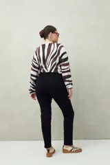 Pantalón chupín negro de tiro alto, confeccionado en denim suave y levemente elástico, con bolsillos delanteros y traseros.