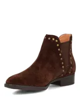 Botines de gamuza color marrón oscuro con diseño tipo chelsea, detalle de tachas metálicas a lo largo del elástico lateral y suela de goma con tacón bajo.