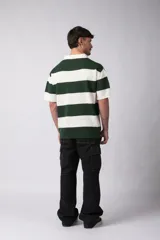 Remera tipo chomba de tejido de punto con diseño de rayas horizontales anchas en tonos beige y crema. Presenta cuello polo con escote en V, mangas cortas y un corte holgado oversize.