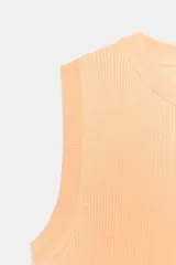 Top crop de tejido de punto color beige claro, con cuello redondo y manga sisa. Presenta acabados en rib en el cuello, sisas y bajo.