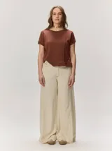Pantalón ancho color beige, con fit holgado desde la cadera hasta el tobillo y distintos cortes verticales decorativos.