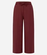 Pantalón tipo pantacourt de corte sastre, color rojo oscuro o vino, con talle alto y lazo ajustable en la cintura. El tejido es ligero y fluido.
