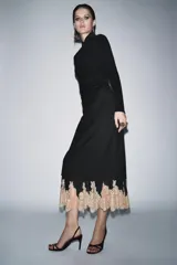 Falda de tiro medio en color negro, con forro interior largo que presenta una aplicación de encaje en tono beige a contraste en el ruedo. Cuenta con cierre de cremallera oculto en la espalda.