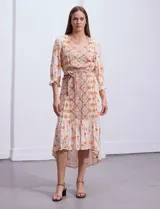 Vestido midi estampado con flores y mandalas en tonos naranja, rojo y celeste, con escote en V, mangas 3/4 con puños fruncidos, cintura elastizada con lazo y ruedo irregular.