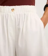 Short runner de corte evasé confeccionado en mezcla de viscosa y lino. Presenta cintura elástica con detalle de botón frontal, bolsillos laterales y bajo redondeado.