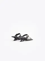 Sandalias de cuero vacuno efecto gastado color negro, con taco de 4 cm, tiras con mini tachas, hebilla metálica y dijes colgantes.