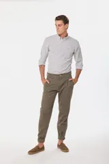 Pantalón de vestir color verde oliva, de corte recto, con bolsillos laterales y traseros. Se ajusta a la cintura con cinturón de cuero marrón.