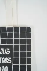 Bolso tote de tela con estampado de rayas verticales rosadas y blancas, laterales y asas en color beige. Presenta la palabra "BONJOUR" en verde en el centro y "INDIAN" en la parte inferior.