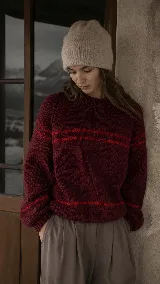 Sweater de punto grueso tejido artesanalmente en lana merino, color bordó con líneas horizontales en contraste de color rojo. Presenta cuello redondo, mangas largas con puños ajustados y silueta relajada.