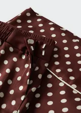 Pantalon palazzo de tejido satinado color bordó con estampado de lunares blancos. Presenta tiro medio, cintura elástica, bolsillos laterales y detalle de ribete en el ruedo.