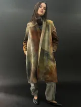 Tapado largo de lana merino con teñido tie-dye en tonos marrones, amarillos y grises. Presenta corte especial en los hombros y bolsillos laterales.