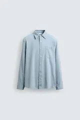 Camisa de corte regular confeccionada en tejido de algodón con efecto lavado. Presenta cuello solapa, cierre frontal de botones, manga larga con puño abotonado y un bolsillo de plastrón en el pecho.