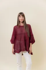 Buzo de tejido liviano con brillo sutil tipo lurex, color beige o dorado claro. Presenta un calce suelto (oversize) con mangas amplias y cuello redondo. El ruedo tiene un detalle de terminación festoneado con pequeños calados.