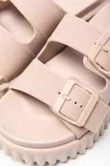 Sandalias tipo mule color beige, con doble tira ajustable con hebillas y suela gruesa acanalada con plataforma.