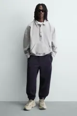 Zapatilla deportiva de estilo running, completamente negra, con capellada de malla y superposiciones sintéticas. Presenta una suela gruesa y voluminosa con diseño segmentado.