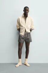 Cárdigan de ajuste relajado, tejido en hilado con lana, color crema. Presenta cuello solapa, manga larga y textura de punto trenzado en todo el cuerpo. Cierre frontal con botones.